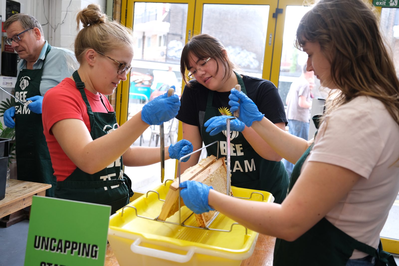 Guests uncapping honeycomb frames together at Hiver
