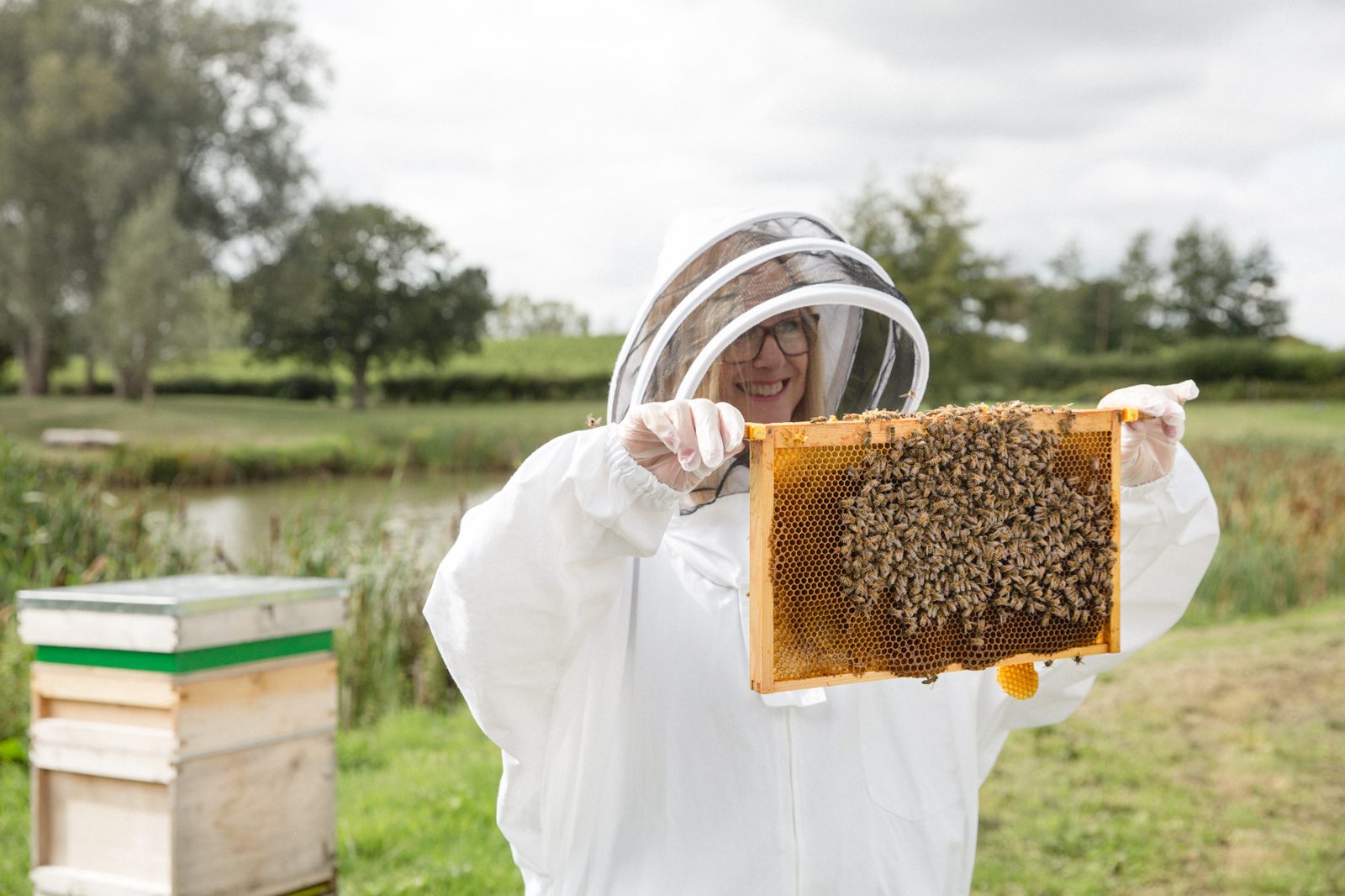 Holding up a frame of bees by the lake at Albourne